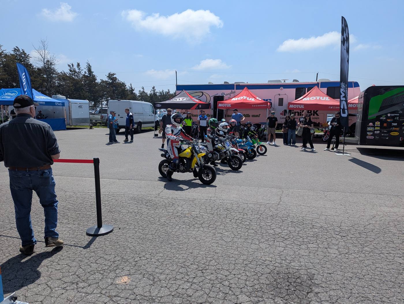 Helmeted minimoto riders lined up in the paddock at Shannonville Motorsport Park